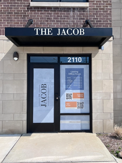  Custom commercial awning over the entrance of The Jacob apartments in Indianapolis with window graphics and leasing office hours signage on the glass doors