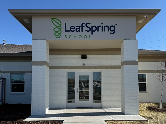 Commercial Awning and Building Sign for LeafSpring Custom commercial awning and large exterior building sign for LeafSpring School in Indianapolis installed above the main entrance on a white brick facade