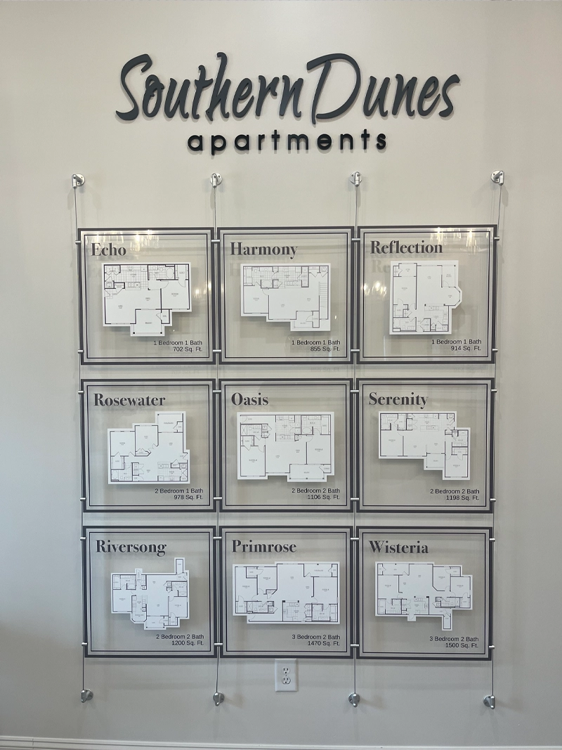 Interior apartment signs for Southern Dunes including a custom wall-mounted floor plan display showing nine unit layouts in acrylic frames with dimensional lettering above