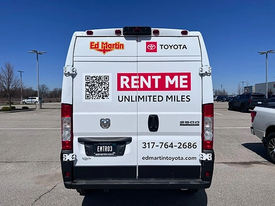 Rear view of a white Ram ProMaster 2500 van for Ed Martin Toyota featuring Rent Me Unlimited Miles graphics, QR code, phone number 317-764-2686, and website edmartintoyota.com, installed by Eye 4 Group in Indianapolis