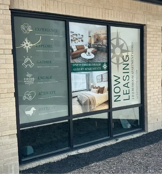 Perforated window vinyl installation for luxury apartment leasing office in Indianapolis showing Now Leasing graphics and interior photos