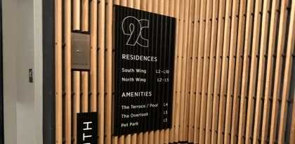ADA-compliant interior wayfinding and directory sign for 9C Residences multi-tenant residential building showing floor-by-floor residences and amenities listing on a wood slat feature wall in Indianapolis, installed by Eye 4 Group